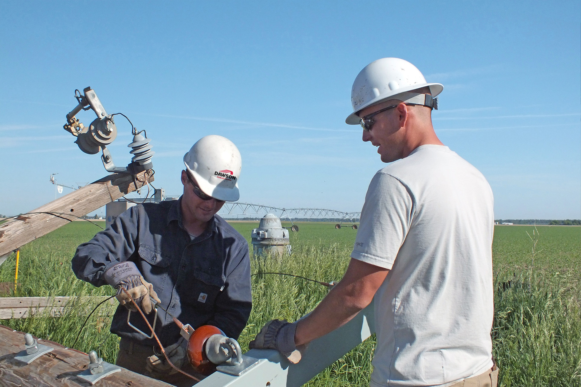 Two Two Dawson Public Power workers, wearing hardhats, working out in the field