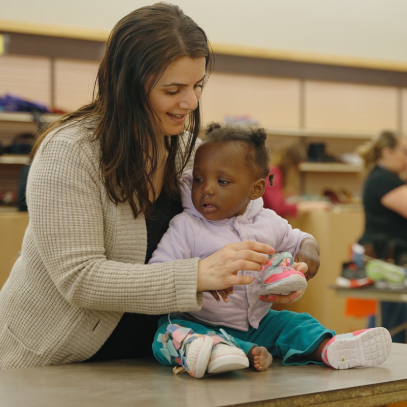 woman putting shoes on baby