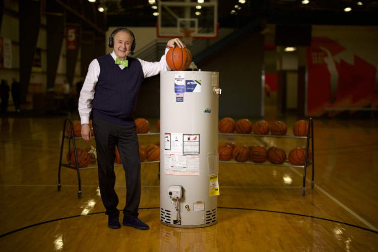 Kent Pavelka posing with a water heater in his broadcasting uniform