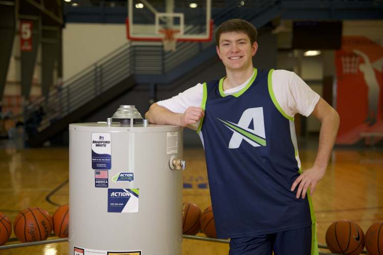 Hukser Men's Basketball player, Pryce Sandfort, posing with a water heater