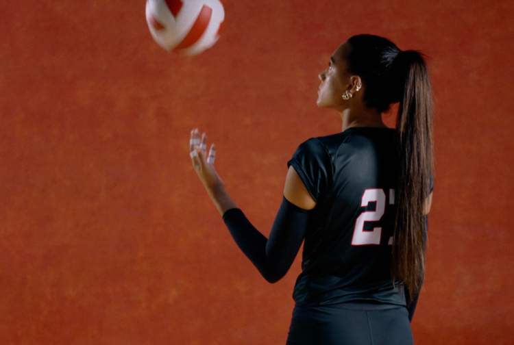 Nebraska Cornhusker Volleyball player, Harper Murray, throwing up an adidas volleyball